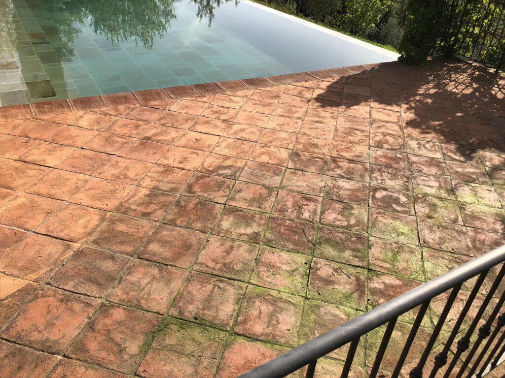 Anwendung von Algacid Grünbelagentferner auf einer veralgten Terrasse zur Vorbereitung der Imprägnierung.